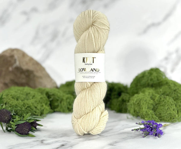 Ball of yarn with a label on a marble surface with greenery in the background