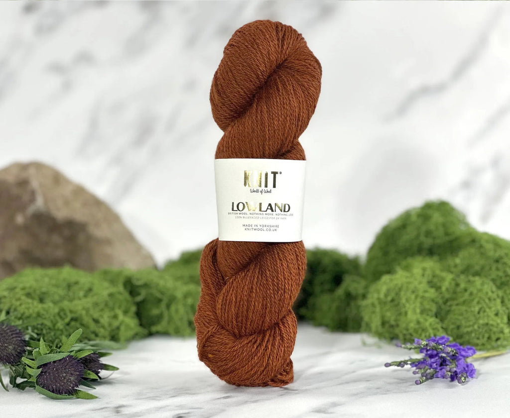 Brown skein of yarn with a label on a white surface with greenery in the background