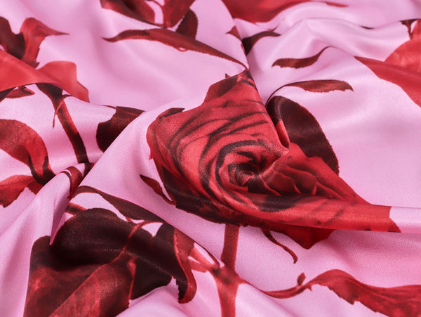 Close-up of red and black floral patterned fabric on a pink background