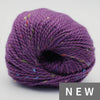 Purple yarn ball with speckles on a light gray background