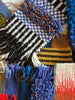 Close-up of a textured fabric with colorful patterns and fringes.