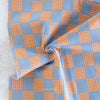 Checkered fabric with orange and blue pattern on a textured surface
