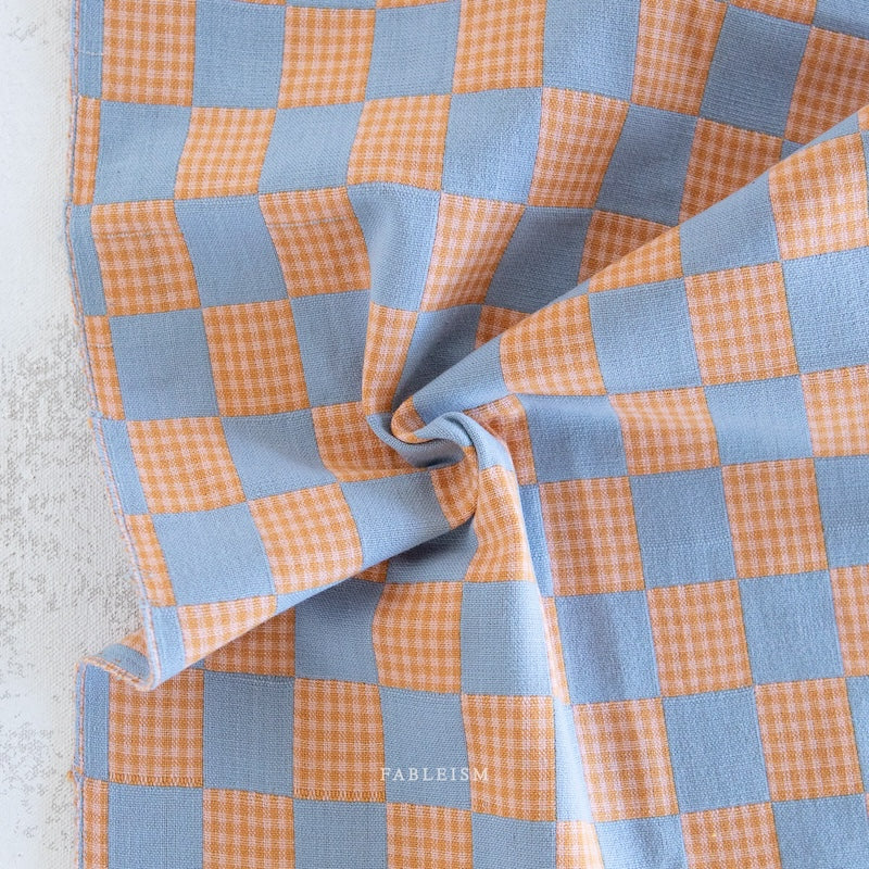 Checkered fabric with orange and blue pattern on a textured surface