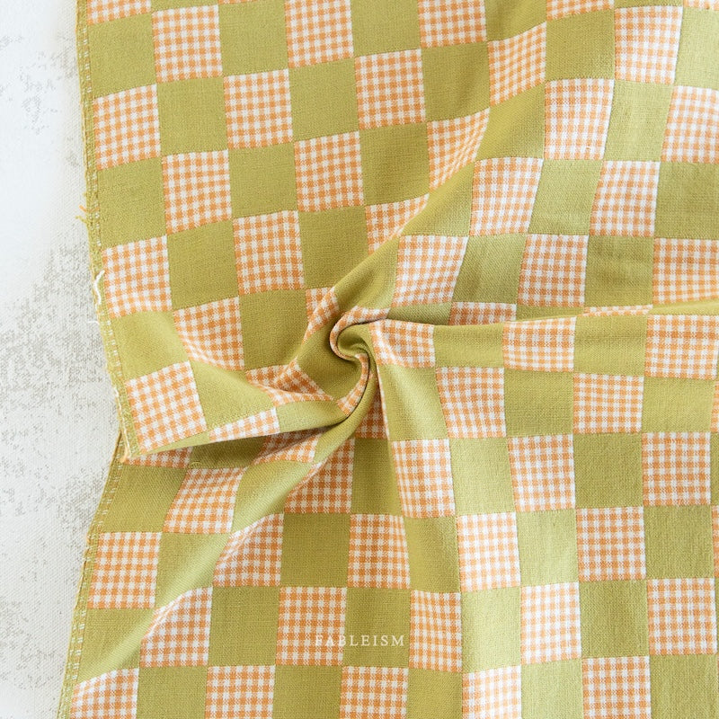Green and orange checkered fabric on a textured surface