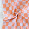 Checkered fabric with orange and gray pattern on a textured surface