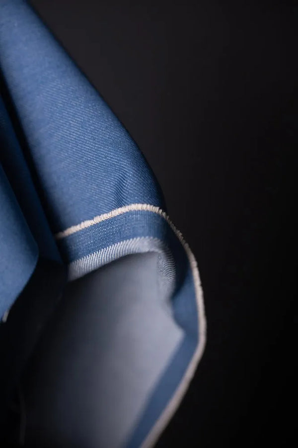 Close-up of a blue fabric with white trim on a dark background