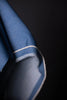 Close-up of a blue fabric with white trim on a dark background
