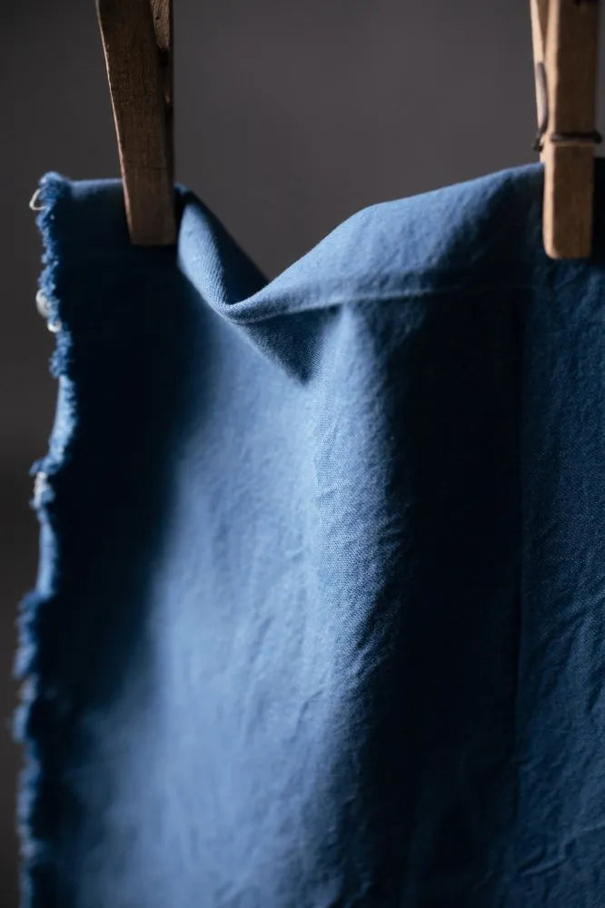 Blue fabric draped over a wooden frame against a dark background