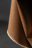 Brown fabric with a frayed edge on a dark background