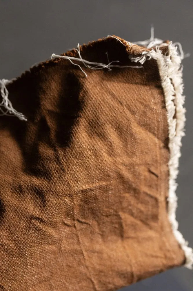 Close-up of brown fabric with frayed edges on a dark background