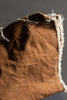 Close-up of brown fabric with frayed edges on a dark background