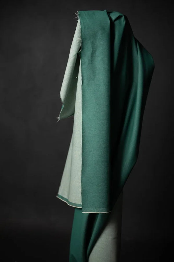 Green fabric draped over a mannequin against a dark background