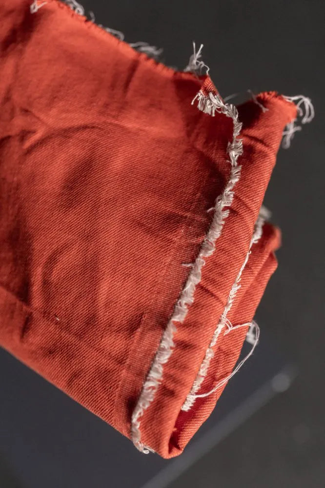 Close-up of a red fabric with frayed edges on a dark background