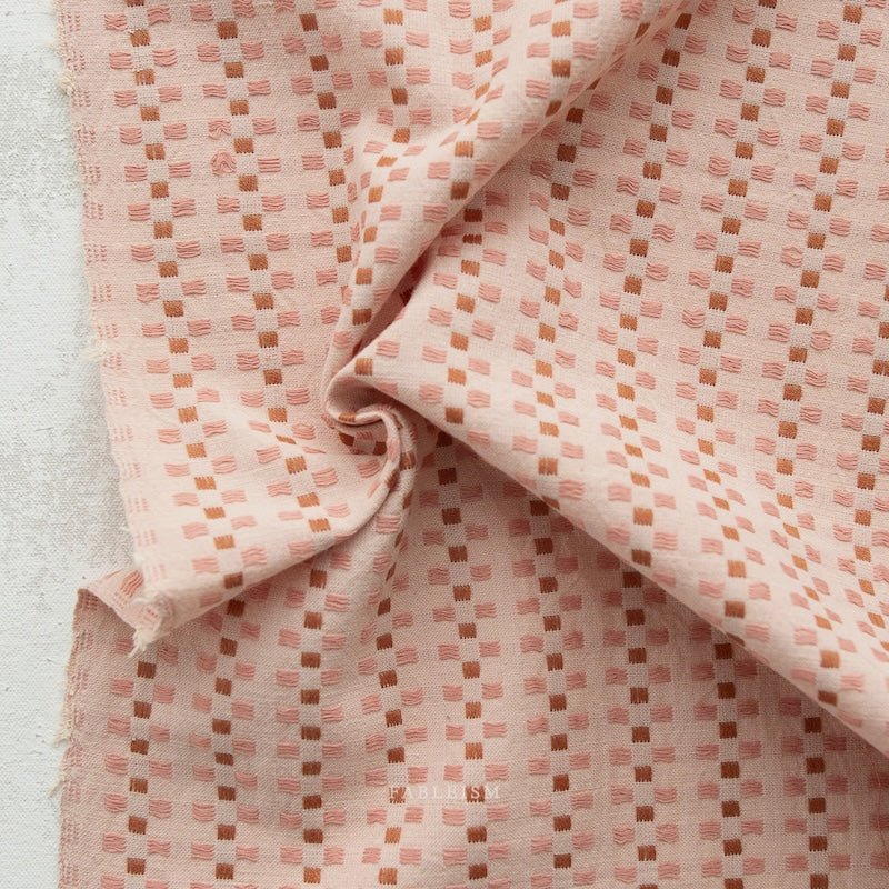 Pink fabric with a subtle pattern on a light gray background