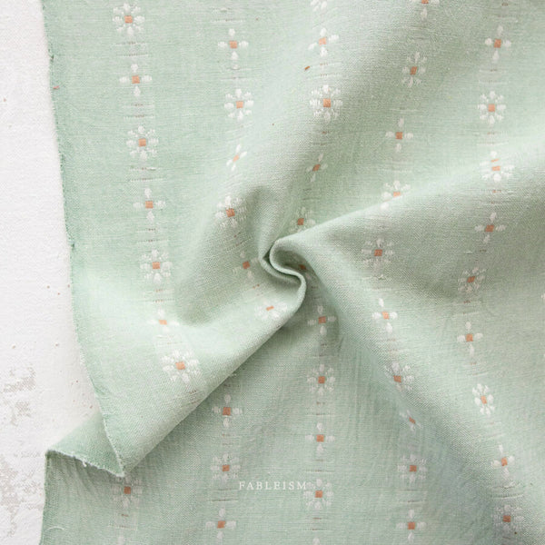 Light green fabric with subtle pattern on a textured surface