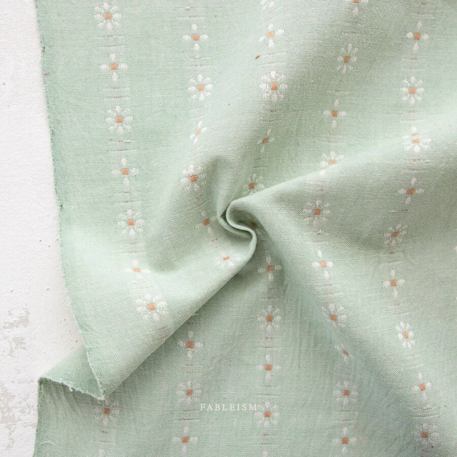 Light green fabric with subtle pattern on a textured surface