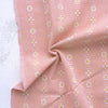 Pink fabric with white floral pattern on a white background