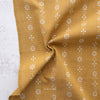 Mustard yellow fabric with white floral patterns on a textured surface