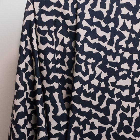 Two pieces of viscose crepe fabric in beige with a geometric pattern and black with a floral pattern, laid flat.