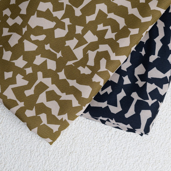 Two pieces of viscose crepe fabric in beige with a geometric pattern and black with a floral pattern, laid flat.