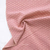 Pink textured fabric with a subtle pattern on a white background