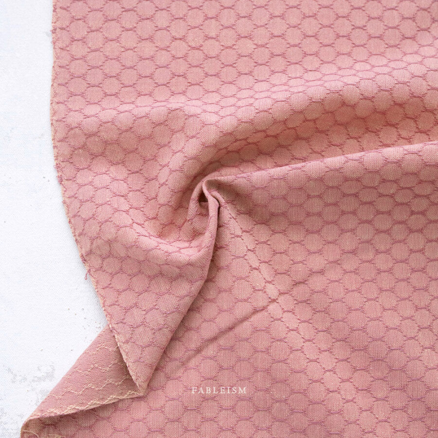 Pink textured fabric with a subtle pattern on a white background