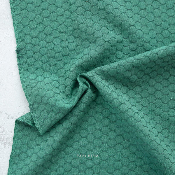 Green fabric with a subtle pattern on a white background, featuring the brand 'Fableism'.