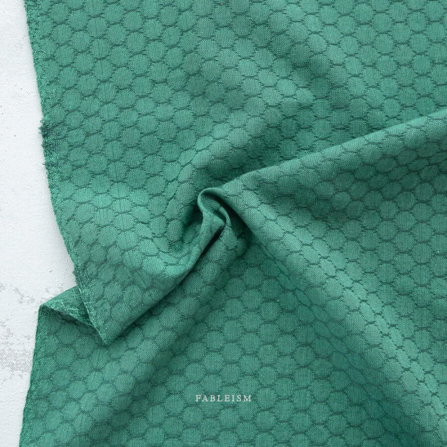 Green fabric with a subtle pattern on a white background, featuring the brand 'Fableism'.