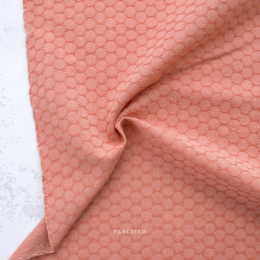 Close-up of pink textured fabric with 'Fableism' branding on a light background