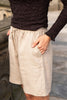 Person wearing a dark sweater and light-colored shorts with a blurred background