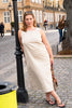Woman in a white dress standing next to a black lamp post on a city street.