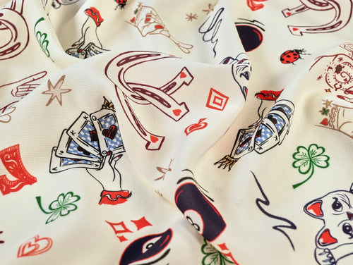 Fabric with playing card and tattoo-style designs on a white background