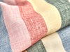 Close-up of fabric with pink, beige, and blue pattern on a textured surface