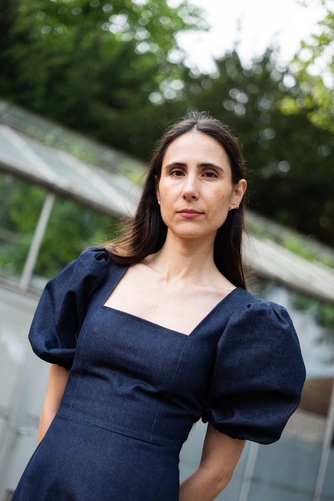 Woman wearing a dark blue dress with puffed sleeves outdoors
