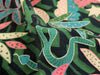 Close-up of fabric with green and pink leaf pattern on black background