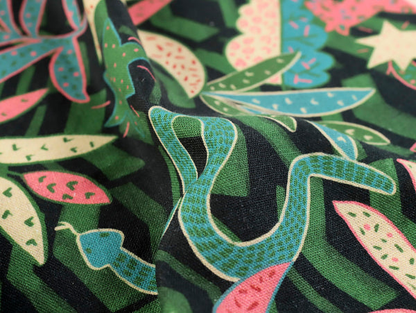 Close-up of fabric with green and pink leaf pattern on black background