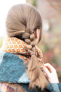 Person with braided hair wearing a patterned scarf in an outdoor setting