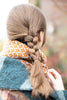 Person with braided hair wearing a patterned scarf in an outdoor setting