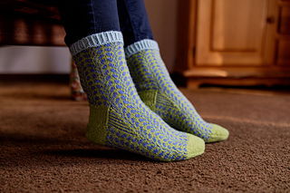 Person wearing green patterned socks on a carpeted floor.
