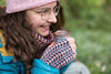 Woman in winter clothing holding a small cup outdoors