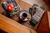 Cozy indoor setting with a cup of coffee, gloves, and an apple on a wooden surface.