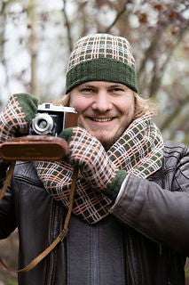Person holding a vintage camera outdoors with a plaid hat and scarf.