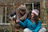 Two people sitting on a bench outdoors, one pouring a drink from a bottle.