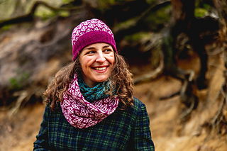 Person wearing a pink knitted hat and scarf in a forest setting