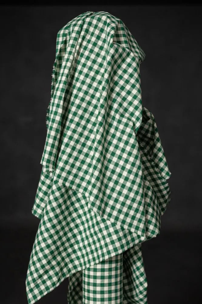 Green and white checkered fabric draped over a person against a black background