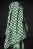 Green and white checkered fabric draped over a person against a black background