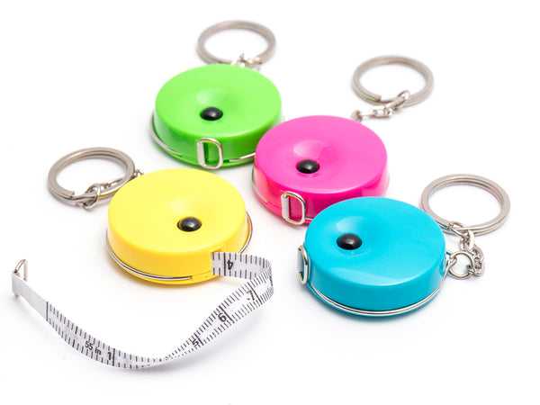 Tape measure key rings in yellow, green, pink and blue on a white background