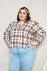 Woman wearing a plaid shirt and light blue jeans against a plain background