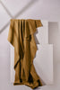 Brown fabric draped over a white geometric sculpture on a light gray background