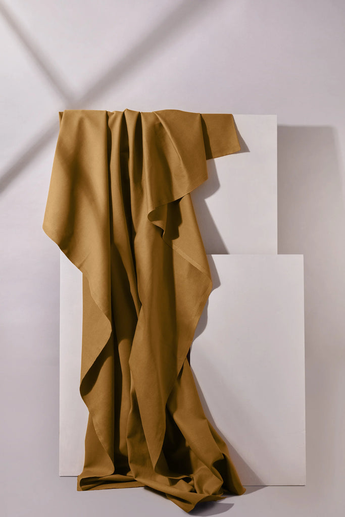Brown fabric draped over a white geometric sculpture on a light gray background
